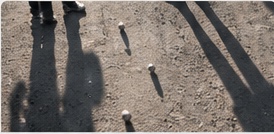 Schatten von Spielern auf dem Boule-Platz